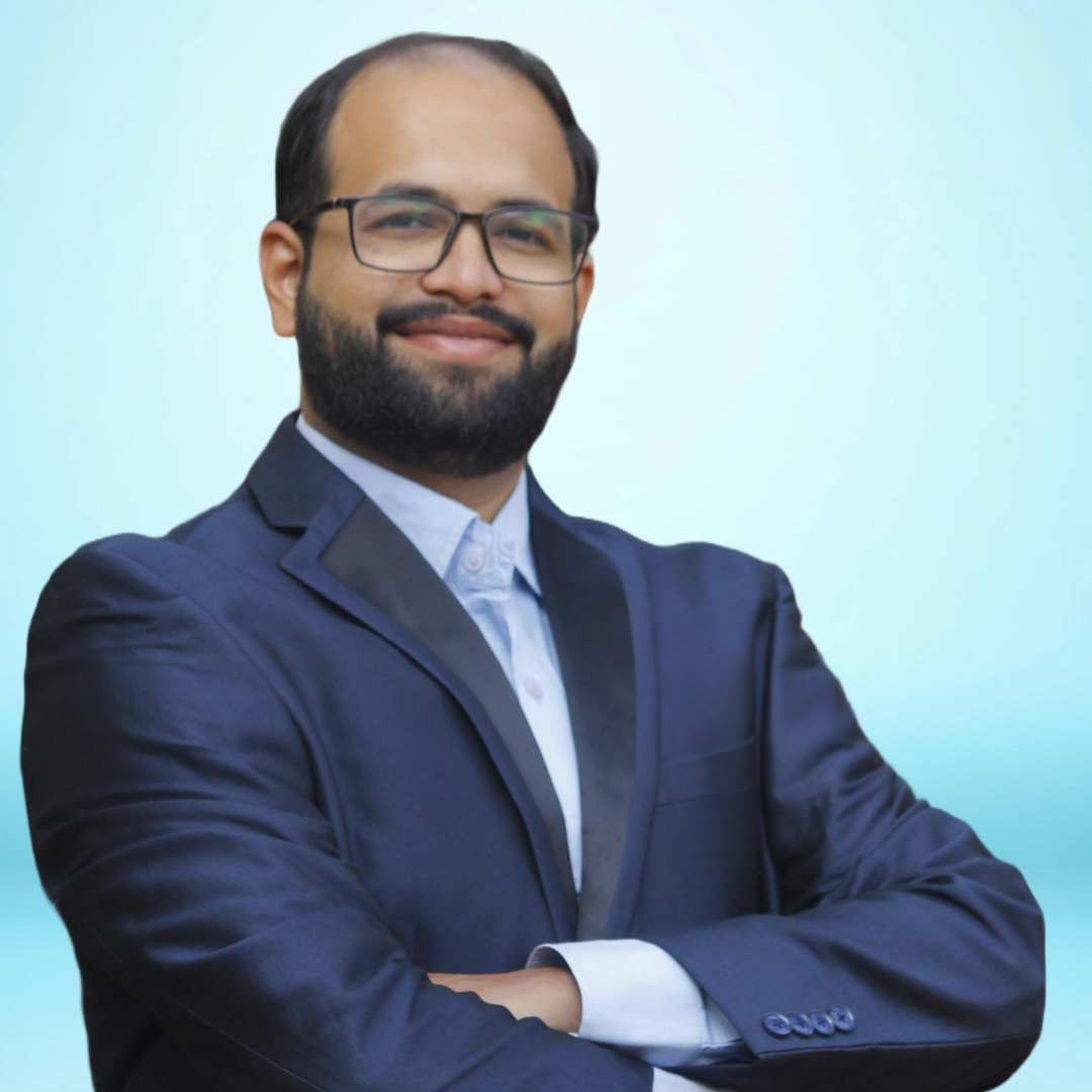 A man in a suit smiling in front of a bookshelf